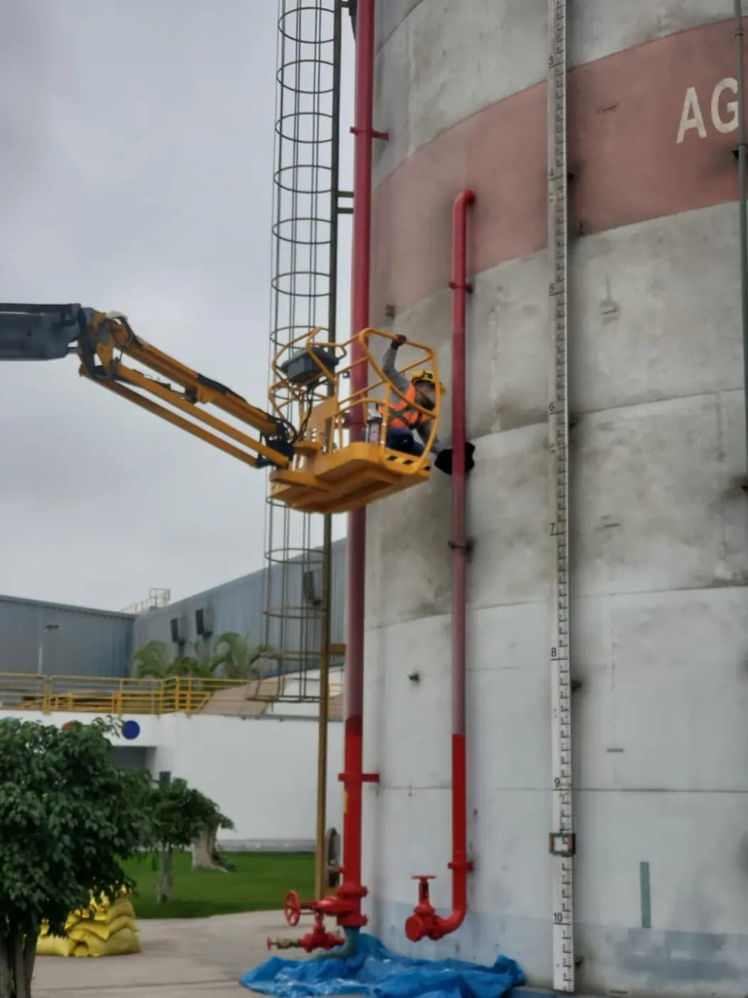 Trabajo en altura con plataforma elevadora en la pared de un tanque industrial