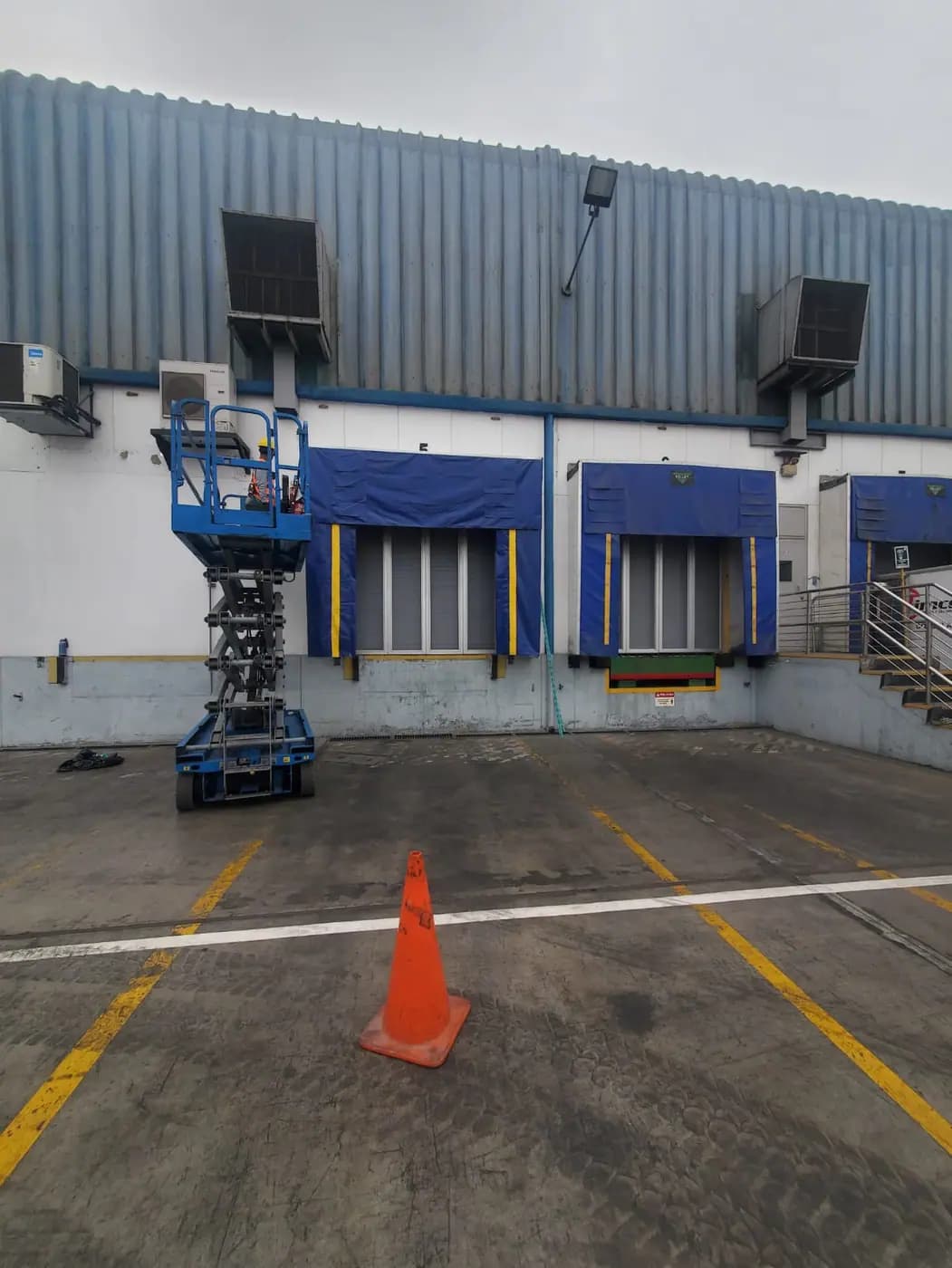 Plataforma de tijera para trabajo en altura en la zona de andenes de un almacén