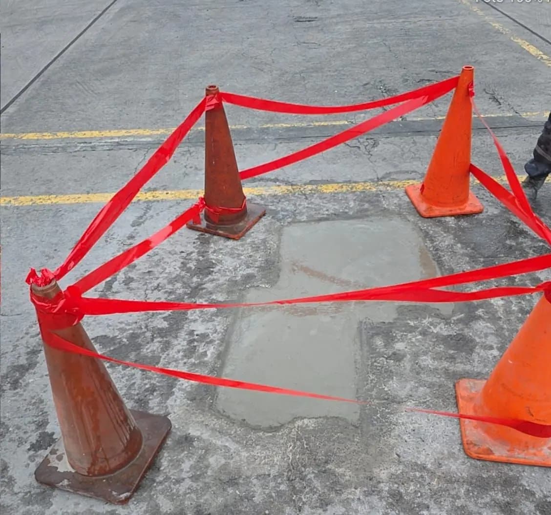 Reparación de piso de concreto con la zona de trabajo delimitada con conos y cinta de seguridad